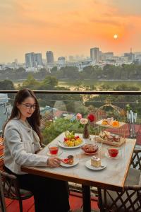 a woman sitting at a table with food on it at Authentic Hanoi Boutique Hotel in Hanoi