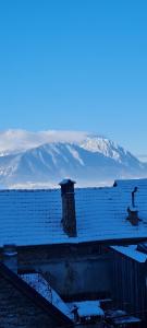 um telhado coberto de neve de uma casa com montanhas ao fundo em Casa Pe Vale em Rasnov