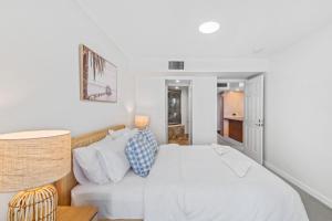 Un dormitorio blanco con una cama y una mesa. en Zanzibar 505, en Mooloolaba 10 fotos más