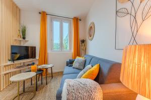 a living room with a blue couch and a tv at LA MAISON DES VIGNES SAINT EMILION in Saint-Émilion
