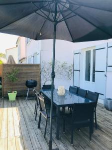 a table and chairs under an umbrella on a deck at Maison paisible in Niort
