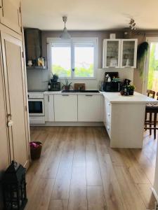 a kitchen with white cabinets and a wooden floor at Maison paisible in Niort