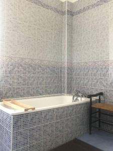 a bath tub in a bathroom with a tiled wall at L'Eglantine bord de mer in Ault