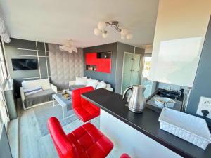 uma cozinha com cadeiras vermelhas e uma sala de estar em Apartament Everest by Managerent em Ustka