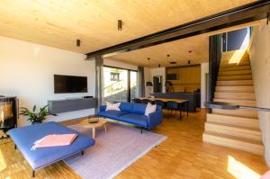ein Wohnzimmer mit einem blauen Sofa und einer Treppe in der Unterkunft Sauerland Lodge - Haus Maxim in Winterberg