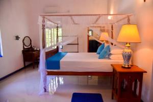 a bedroom with a canopy bed with a lamp and a table at Mishthana Canal Resort in Bentota