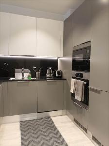 a kitchen with white cabinets and a microwave and a rug at Modern skyscraper apartment by metro and sea Helsinki in Helsinki