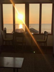 a room with a table and chairs and the sunset at L'Eglantine bord de mer in Ault