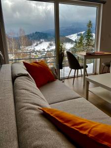a couch in a living room with a large window at Apartamenty Widokowe Na Szczycie in Korbielów