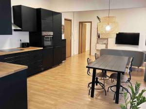 una cocina con armarios negros y una mesa con sillas en Downtown Apartment, en Kavala