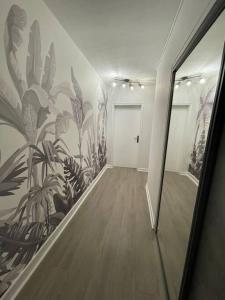 a hallway with a mural of plants on the wall at Le Charmeur * * * in Aurillac