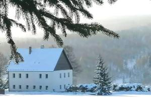 a white house with a snow covered roof at Chata Krušnohorka in Kovářská