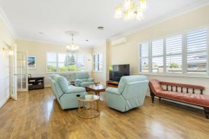 a living room with blue chairs and a couch and a tv at Dory's Beach House - Executive Escapes in Safety Bay