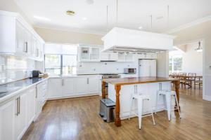 a kitchen with white cabinets and a wooden table at Dory's Beach House - Executive Escapes in Safety Bay
