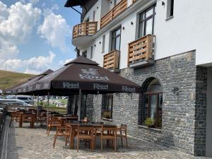 a restaurant with tables and umbrellas in front of a building at Hotel Dia Lin in Borşa