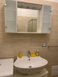 Appartamento a Campobasso في كامبوباسو: حمام مع حوض أبيض ومرآة