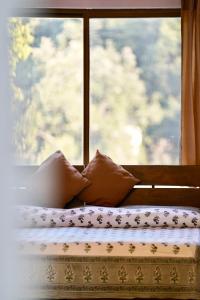 a bed with pillows in front of a window at The Flying Squirrel Bandhavgarh in Umariā