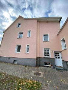 マクデブルクにあるFreundliche Ferienwohnungの白窓と私道のあるピンクの建物