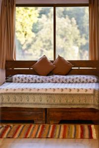 2 camas sentadas frente a una ventana en The Flying Squirrel Bandhavgarh en Umariā
