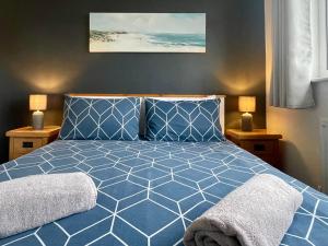 a bedroom with a blue bed with two lamps at Bungalow33 Benllech in Benllech