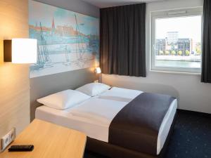 a hotel room with a bed and a desk and a window at B&B Hotel Kiel-City in Kiel