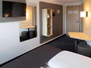 a room with a bed and a desk and a mirror at B&B Hotel Kiel-City in Kiel