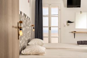 a bedroom with a bed with two pillows and a window at Palm in Ios Chora