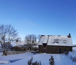 une vieille maison avec de la neige sur son toit dans l'établissement Gîte du Milan royal, à Le Monteil