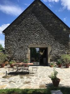 a stone building with a table and benches in front of it at Gîte du Milan royal in Le Monteil