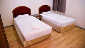 two beds in a small room with wood floors at Sogo Hotel 2 in Labuan