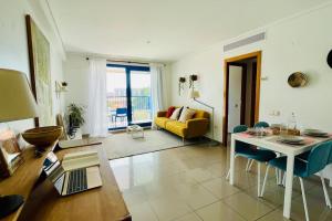 ein Wohnzimmer mit einem Tisch und einem gelben Sofa in der Unterkunft Apto con vistas a la playa de La Patacona in Valencia