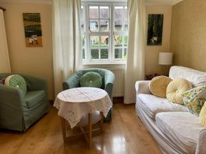 een woonkamer met een bank, stoelen en een tafel bij The Hidden Cottage in Londen