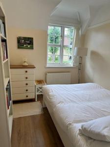a bedroom with a bed and a dresser and a window at The Hidden Cottage in London
