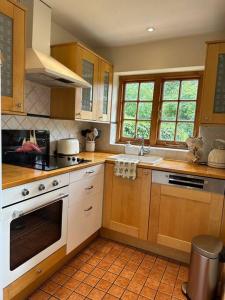 een keuken met houten kasten en witte apparaten bij The Hidden Cottage in Londen
