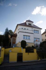 a white house with a yellow fence in front of it at Kernberg Apartment Jena in Jena