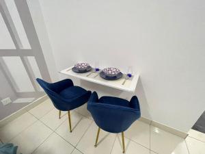 a white table with blue chairs and plates on it at Lenore & Myna Suite at Alanis Residence Sepang, KLIA Homestay Apartment in Sepang
