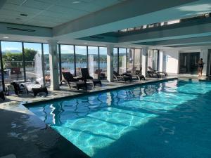 a swimming pool in a building with chairs and water at The Penthouse Bowness Luxury Loft Jacuzzi Bath & Complimentary Lakeview Spa Membership in Bowness-on-Windermere