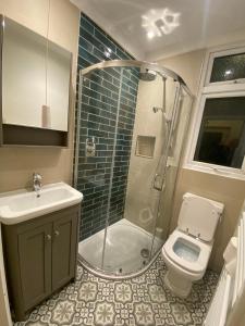 a bathroom with a shower and a toilet and a sink at Bikki Apartments - 2 Bedroom in Harrow