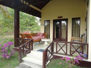 a porch of a house with a couch and flowers at Adinda Bungalows in Gili Air