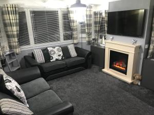 a living room with a couch and a fireplace at Hot Tub Accommodation Static North Wales in Kinmel Bay