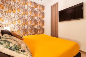 a bedroom with a yellow bed and a tv at VL Luxury Apartment - Housea in Polignano a Mare