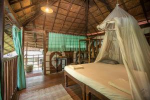 a bedroom with a bed with a mosquito net at Bhakti Kutir in Palolem