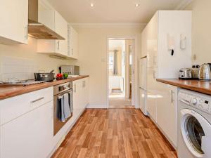 cocina con armarios blancos y suelo de madera en 3 Bed in Mudeford 93459 en Christchurch