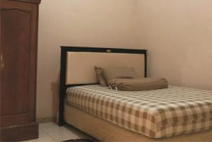 a bedroom with a bed with a checkered blanket at Griya Erlangga in Kediri