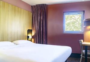 a bedroom with two beds and a window at B&B HOTEL Nîmes Centre Arènes in Nîmes