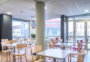 - une salle à manger avec des tables, des chaises et des fenêtres dans l'établissement B&B HOTEL Nîmes Centre Arènes, à Nîmes