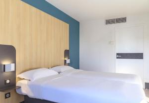 - un grand lit blanc dans une chambre aux murs bleus dans l'établissement B&B HOTEL Nîmes Centre Arènes, à Nîmes
