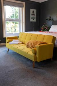 a yellow couch in a bedroom with a bed at The Plough Inn in Marsham