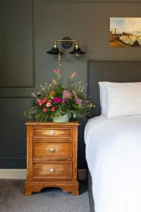 a bedroom with a dresser with a flower arrangement on it at The Plough Inn in Marsham