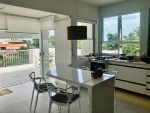 a kitchen with a white table and chairs and windows at Penthouse with private pool & amazing views in Salvador